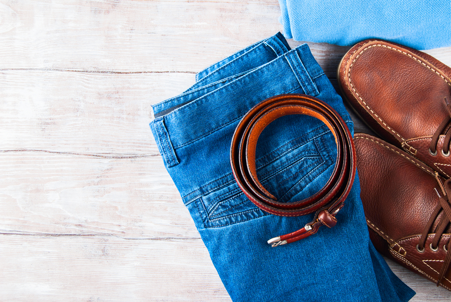 Man's clothes flat lay with blue jeans, T-shirt, pullover, leather shoes and belt